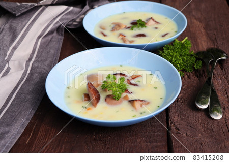 Creamy soup with boletus mushroom and herbs on wooden table 83415208