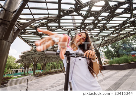 Young beautiful woman teasing and showing tongue at camera in park 83415344