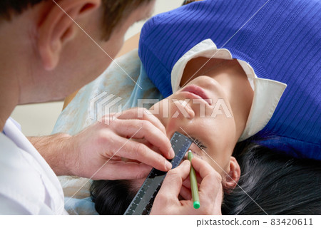 plastic surgeon and young woman with correction lines before cosmetic surgery, drawing lines on eyes plastic surgeon and young woman with correction lines before cosmetic surgery, drawing lines on eyes 83420611