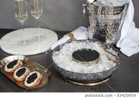 Black caviar in can on ice, caviar sandwich on golden plate, champagne in glass Black caviar in can on ice, caviar sandwich on golden plate, champagne in glass 83420959