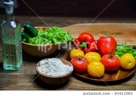 wooden bowl of flour, vegetable oil and vegetables on the kitchen table 83421065