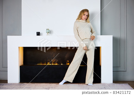 Electric fireplace with slender woman who stands in living room. Electric fireplace with slender woman who stands in living room. 83421172