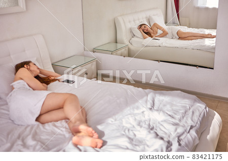 Back view of woman in towel who lies on bed. 83421175