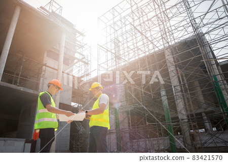 Engineer discussing with foreman about project in building construction site. 83421570