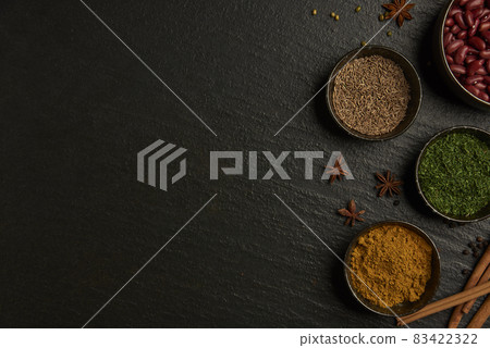 spices concept the varieties of colors and types of spices set into small bowl on the black background with a wooden spoon 83422322