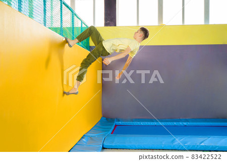 Teenage boy jumping on trampoline park in sport center Teenage boy jumping on trampoline park in sport center 83422522