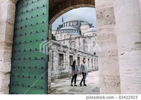 Traveling couple near the mosque. Beautiful mosque in Istanbul. Wedding trip the newlyweds. Tourists in Turkey. Follow me. Boy and girl holding hands. Tourists on the tour. Man and woman in the mosque 83422923