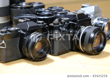 Two single-lens reflex cameras lined up and a lens lined up behind Two single-lens reflex cameras lined up and a lens lined up behind 83423258