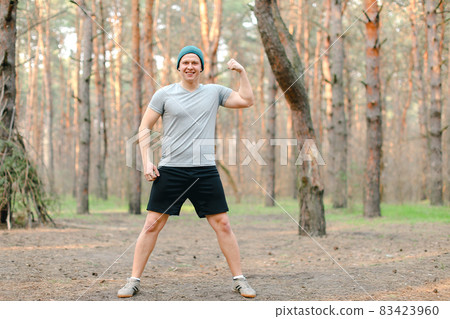 Young man doing workout in morning park and showing biceps. Young man doing workout in morning park and showing biceps. 83423960