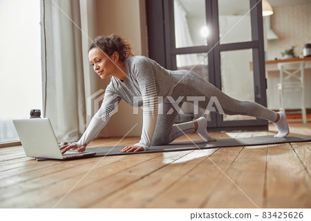 Cheerful woman preparing for online workout at home 83425626