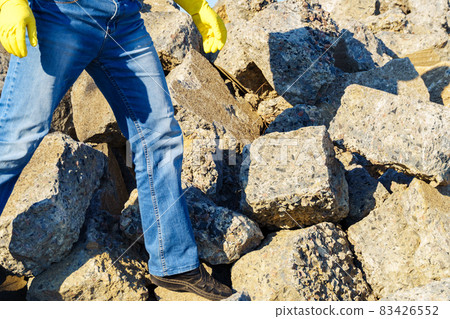 a man works with a pile of stones and broken pieces of concrete, carries construction debris a man works with a pile of stones and broken pieces of concrete, carries construction debris 83426552