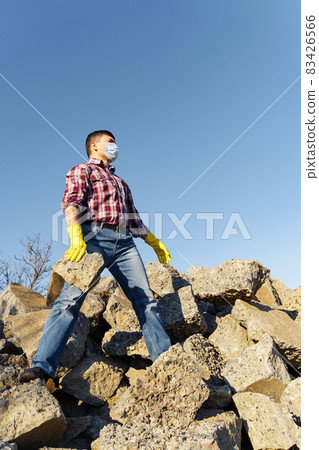 a man works with a pile of stones and broken pieces of concrete, carries construction debris a man works with a pile of stones and broken pieces of concrete, carries construction debris 83426566
