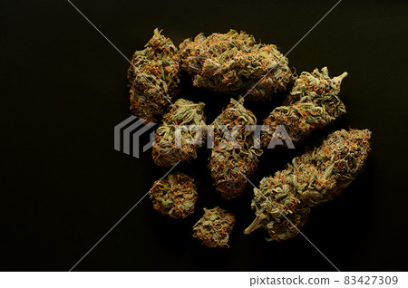 Marijuana buds, top view. Medicinal cannabis flowering blooms on black background. Marijuana buds, top view. Medicinal cannabis flowering blooms on black background. 83427309