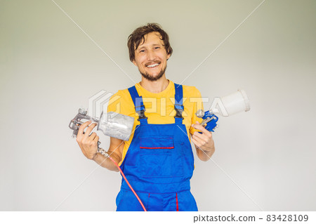 Painter in work clothes with a paint spray gun 83428109