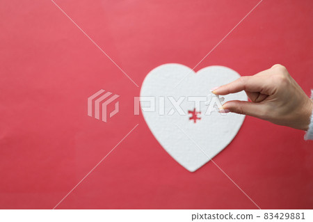 Top view of female hand holding missing piece of heart puzzle jigsaw 83429881