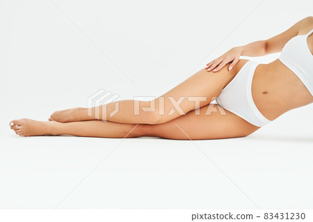Slim tanned woman's legs on white studio background Slim tanned woman's legs on white studio background 83431230