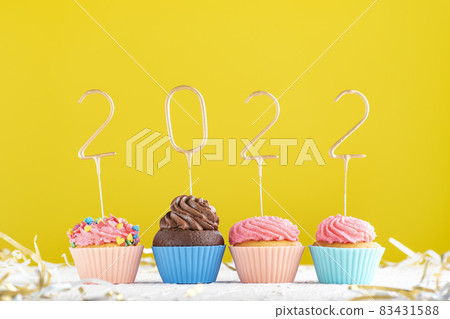 Homemade muffins decorated with 2022 numbers on yellow background. Happy New Year, Merry Christmas concept. Homemade muffins decorated with 2022 numbers on yellow background. Happy New Year, Merry Christmas concept. 83431588