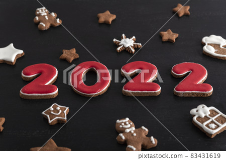Inscription 2022 from gingerbread cookie. Christmas bacing, black background 83431619
