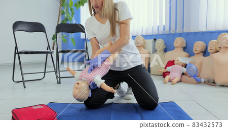 Instructor performs CPR on baby training doll. Woman instructor show how to do CPR on a doll dummy for cardiopulmonary reanimation training. 83432573
