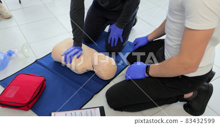 Closeup of students practicing CPR chest compression on teen dummy. 83432599