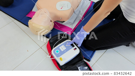CPR training medical procedure workshop. Demonstrating chest compressions and use of AED automatic defibrillator on CPR doll CPR training medical procedure workshop. Demonstrating chest compressions and use of AED automatic defibrillator on CPR doll 83432642