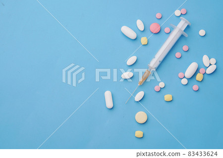 syringe and pills on blue background, close up 83433624