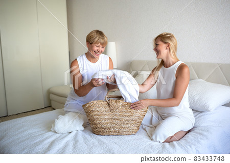 woman with mom disassemble the laundry while sitting on the bed in the bedroom 83433748