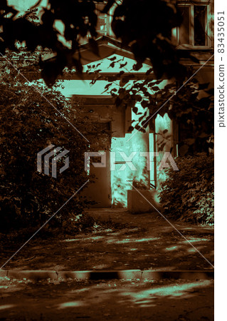 The house is old in the horror style. Scary horrible mystical entrance door to the entrance to the building with dark windows among tree branches with paronormal shadows and strange moonlight The house is old in the horror style. Scary horrible mystical entrance door to the entrance to the building with dark windows among tree branches with paronormal shadows and strange moonlight 83435051