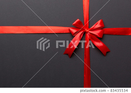 Top view of Red ribbon rolled and red bow isolated on colored background. Flat lay with copy space 83435534