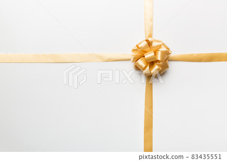Top view of gold ribbon rolled and yellowbow isolated on colored background. Flat lay with copy space Top view of gold ribbon rolled and yellowbow isolated on colored background. Flat lay with copy space 83435551