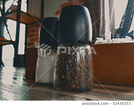 Glass pepper shaker on a wooden table in a cafe Glass pepper shaker on a wooden table in a cafe 83436353