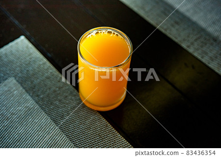 Orange juice in a glass Full glass of orange juice close-up. Fresh orange juice on wooden table in out of focus unidentified restaurant in the morning in summer Orange juice in a glass Full glass of orange juice close-up. Fresh orange juice on wooden table in out of focus unidentified restaurant in the morning in summer 83436354