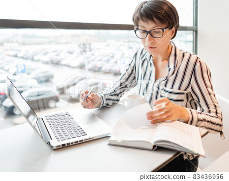 Business woman works with laptop and paper organiser in co-working center. Workplace for freelancers in business center. Business woman works with laptop and paper organiser in co-working center. Workplace for freelancers in business center. 83436956