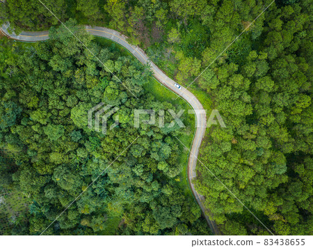 Aerial view of car on the road cut throug green forest in the highland mountains in Chiang Rai province, Thailand. The highland of Chiang Rai is a popular destination during the cold weather season. Aerial view of car on the road cut throug green forest in the highland mountains in Chiang Rai province, Thailand. The highland of Chiang Rai is a popular destination during the cold weather season. 83438655