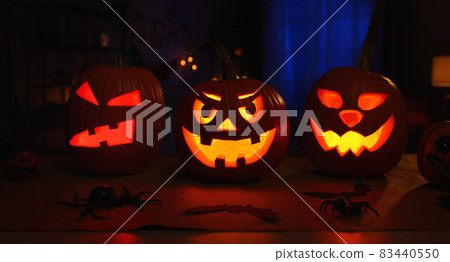 Spooky halloween home decor in dark room decorated with carved pumpkins and spiders 83440550