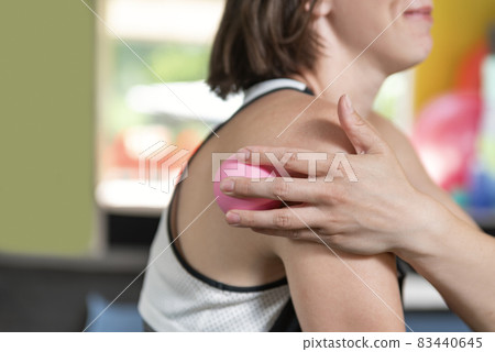 Young sports girl does massage with myofascial ball. Myofascial release with foam roller. Self-massage. 83440645