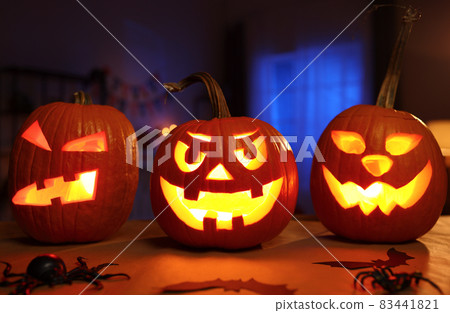 Spooky halloween home decor in dark room decorated with carved pumpkins and spiders Spooky halloween home decor in dark room decorated with carved pumpkins and spiders 83441821