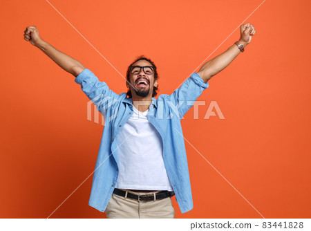 Excited young african american man winner raising arms with clenched fists and celebrating success Excited young african american man winner raising arms with clenched fists and celebrating success 83441828