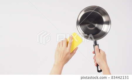 Pot cleaning. Man hand on white background cleaning the non stick pot with handy dish washing sponge which yellow color on the soft side and green on hard side for hygiene after cook. Electric pot. Pot cleaning. Man hand on white background cleaning the non stick pot with handy dish washing sponge which yellow color on the soft side and green on hard side for hygiene after cook. Electric pot. 83442131