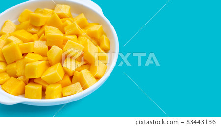Tropical fruit, Mango cube slices in white bowl on blue background. 83443136