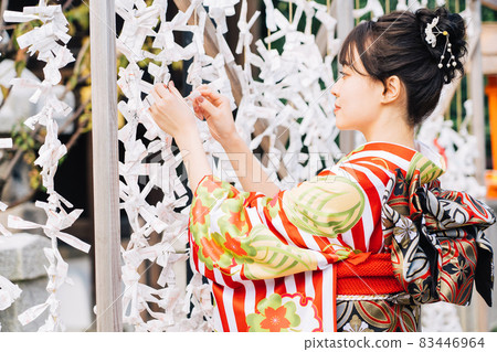 A woman in a kimono tying a fortune A woman in a kimono tying a fortune 83446964