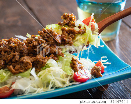 A close-up of Okinawan taco rice. Spicy minced meat, lettuce, tomato and cheese topped with rice A close-up of Okinawan taco rice. Spicy minced meat, lettuce, tomato and cheese topped with rice 83447444