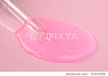 Pipette with fluid hyaluronic acid on pink background. Cosmetics and healthcare concept closeup. Dose of serum or retinol with air bubbles. Flat lay. Luxury gel or beauty product presentation in macro 83447988