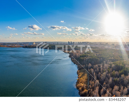 Autumn forest on lake shore at sunset and city on horizon, auerial view Autumn forest on lake shore at sunset and city on horizon, auerial view 83448207