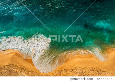 Seascape top view. Panoramic view of the sea waves. Foamy waves roll over the seashore. A vivid picture of marine nature. Stormy oceanic tide. Beaches of Indonesia. Sea foam. Copy space Seascape top view. Panoramic view of the sea waves. Foamy waves roll over the seashore. A vivid picture of marine nature. Stormy oceanic tide. Beaches of Indonesia. Sea foam. Copy space 83448482