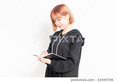 Young woman writing notes in a notebook 83449786