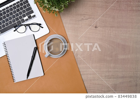 Simple workspace with laptop computer, notebook and coffee cup on wooden table. Simple workspace with laptop computer, notebook and coffee cup on wooden table. 83449838