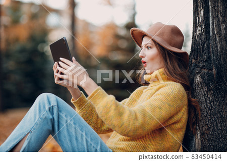 Young woman model in autumn park with yellow foliage maple leaves. Fall season fashion. 83450414