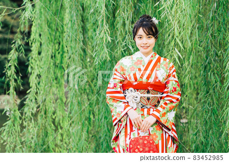 A woman in a kimono (furisode) standing under a willow tree A woman in a kimono (furisode) standing under a willow tree 83452985