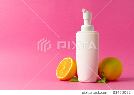 Cosmetic bottle with sliced citrus fruits on bright pink background 83453052